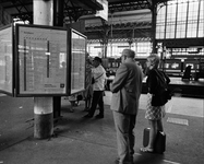 76407 Afbeelding van enkele reizigers bij het vertrektijdenbord op het perron van het Centraal Station van de N.S. te ...